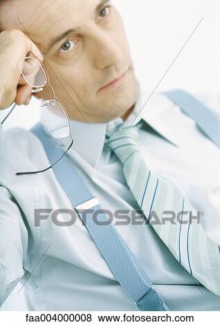 Man holding glasses, leaning on hand, thinking View Large Photo Image Stock Photo - Man holding glasses, leaning on hand, thinking. Fotosearch