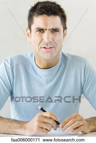 Man holding pen and furrowing brow View Large Photo Image Stock Image - Man holding pen and furrowing brow. Fotosearch