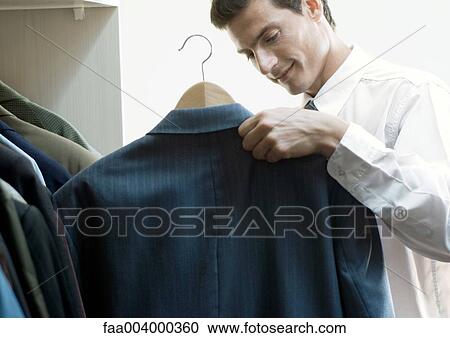 Man holding up jacket on hanger View Large Photo Image Stock Image - Man holding up jacket on hanger. Fotosearch
