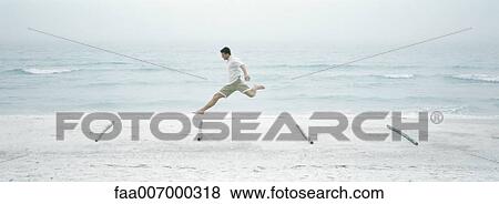 Man jumping over logs on beach, side view View Large Photo Image Stock Photo - Man jumping over logs on beach, side view. Fotosearch