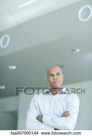 Picture - Man looking away, arms folded, portrait. Fotosearch