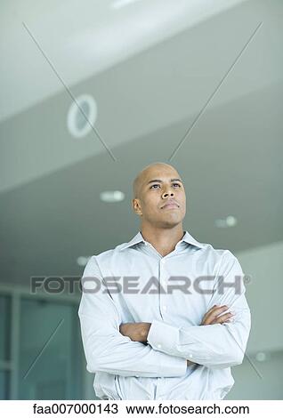 Stock Image - Man looking away, arms folded, portrait. Fotosearch