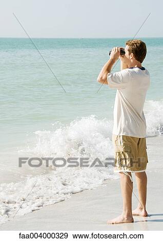 Man looking out to sea with binoculars View Large Photo Image Stock Photo - Man looking out to sea with binoculars. Fotosearch