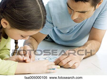 Stock Photography - Man lying on floor drawing with daughter. Fotosearch
