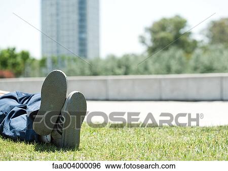 Man lying on grass in city park View Large Photo Image Stock Photograph - Man lying on grass in city park. Fotosearch
