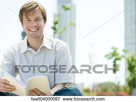 Man sitting in city park with book View Large Photo Image Stock Photo - Man sitting in city park with book. Fotosearch