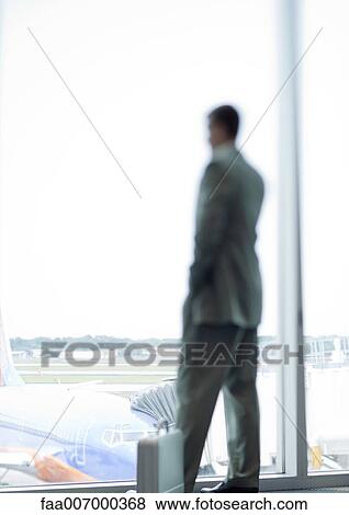 Man standing by window in airport View Large Photo Image Stock Photo - Man standing by window in airport. Fotosearch