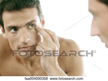 Man touching edge of eye in mirror View Large Photo Image Stock Photo - Man touching edge of eye in mirror. Fotosearch