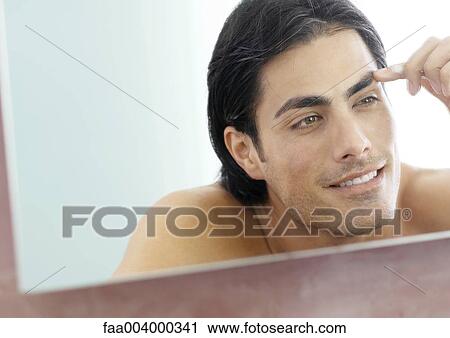Man touching eyebrow in mirror View Large Photo Image Stock Image - Man touching eyebrow in mirror. Fotosearch