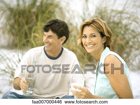 Mature couple drinking water on beach View Large Photo Image Stock Photograph - Mature couple drinking water on beach. Fotosearch