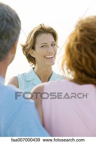Mature woman smiling at friends View Large Photo Image Stock Photo - Mature woman smiling at friends. Fotosearch