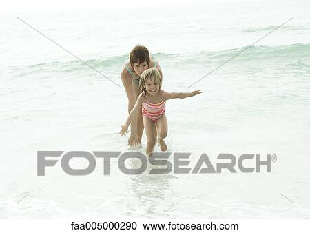 Stock Image - Mother and daughter in water at beach. Fotosearch