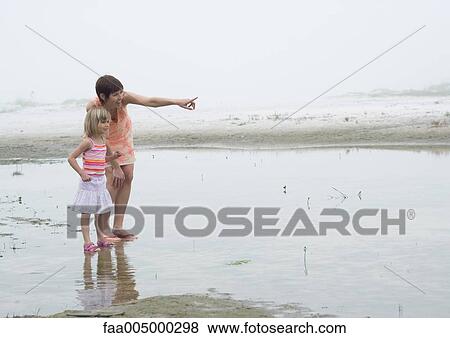 Mother and daughter on beach, mother pointing to distance View Large Photo Image Stock Photo - Mother and daughter on beach, mother pointing to distance. Fotosearch