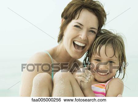 Stock Photograph - Mother holding daughter at the beach, close-up. Fotosearch