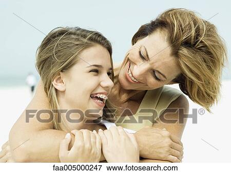 Mother with arms around teenage daughter, smiling over her shoulder View Large Photo Image Stock Photo - Mother with arms around teenage daughter, smiling over her shoulder. Fotosearch