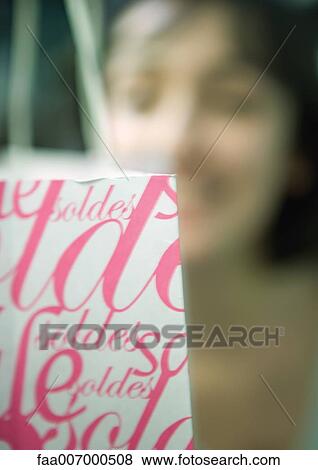 Part of shopping bag, person's face in background View Large Photo Image Stock Photo - Part of shopping bag, person's face in background. Fotosearch
