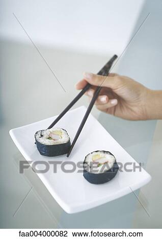 Picking up sushi with chopsticks View Large Photo Image Stock Image - Picking up sushi with chopsticks. Fotosearch