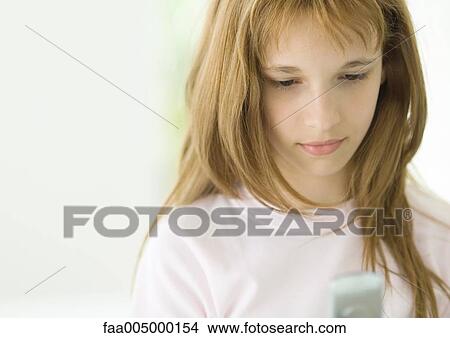 Picture - Preteen girl looking at cell phone. Fotosearch