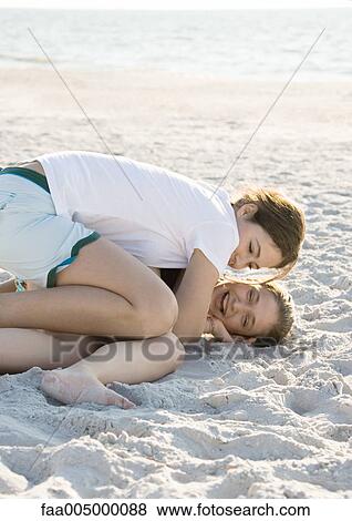 Stock Photo - Preteen girls tickling each other in sand. Fotosearch