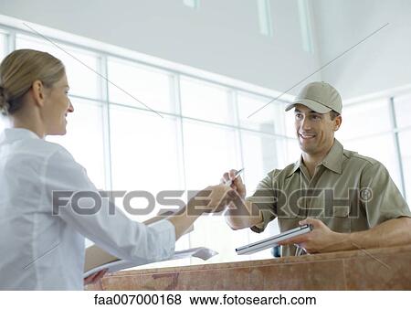 Stock Photo - Receptionist handing pen to delivery man. Fotosearch