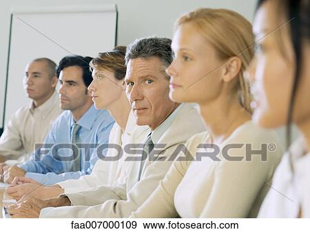 Stock Photo - Row of business people, one mature businessman looking at camera. Fotosearch
