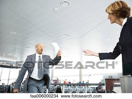 Rushing businessman holding up ticket for airline attendant View Large Photo Image Picture - Rushing businessman holding up ticket for airline attendant. Fotosearch