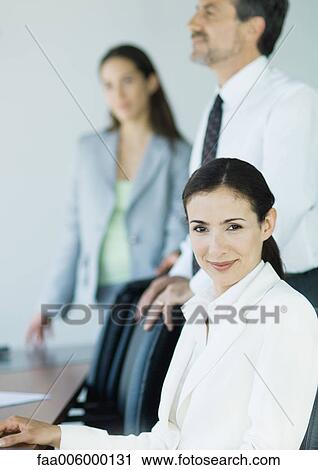 Three business colleagues smiling at camera, focus on foreground View Large Photo Image Stock Image - Three business colleagues smiling at camera, focus on foreground. Fotosearch