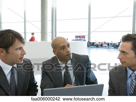 Three businessmen talking in airport View Large Photo Image Stock Image - Three businessmen talking in airport. Fotosearch