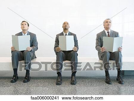 Three men in suits sitting on bench, holding up open folders, and looking up View Large Photo Image Stock Image - Three men in suits sitting on bench, holding up open folders, and looking up. Fotosearch