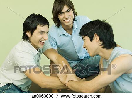 Stock Photo - Three young men clasping each others' hands. Fotosearch