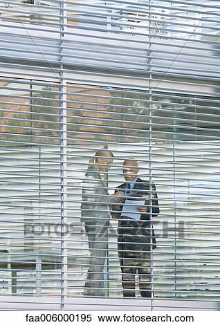 Two business colleagues standing near glass wall, seen from exterior View Large Photo Image Stock Photography - Two business colleagues standing near glass wall, seen from exterior. Fotosearch