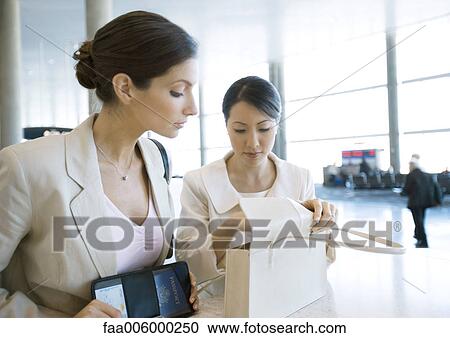Two businesswomen looking through purse in airport View Large Photo Image Stock Image - Two businesswomen looking through purse in airport. Fotosearch