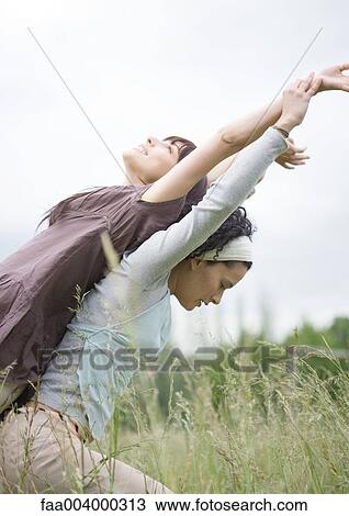 Two female friends exercising back to back outdoors View Large Photo Image Stock Image - Two female friends exercising back to back outdoors. Fotosearch