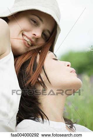 Two female friends outdoors, one leaning against the other View Large Photo Image Stock Image - Two female friends outdoors, one leaning against the other. Fotosearch