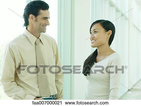 Two office workers talking in hallway View Large Photo Image Stock Image - Two office workers talking in hallway. Fotosearch