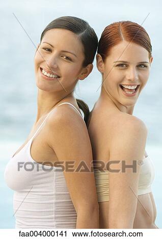 Two women back to back, smiling View Large Photo Image Stock Image - Two women back to back, smiling. Fotosearch