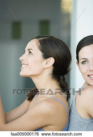 Two young female friends, back to back View Large Photo Image Stock Photograph - Two young female friends, back to back. Fotosearch