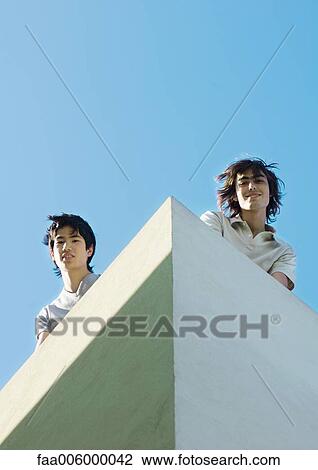 Two young men, low angle view with sky in background View Large Photo Image Stock Image - Two young men, low angle view with sky in background. Fotosearch