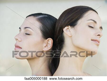 Stock Photo - Two young women back to back with eyes closed, side view. Fotosearch