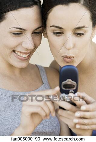Two young women looking at cell phone together View Large Photo Image Stock Image - Two young women looking at cell phone together. Fotosearch