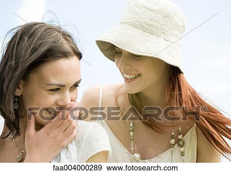 Two young women smiling, one covering mouth View Large Photo Image Stock Photo - Two young women smiling, one covering mouth. Fotosearch