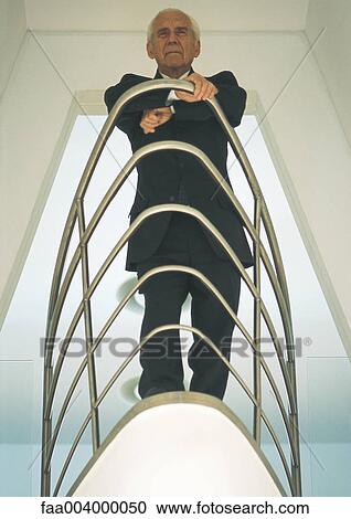 White-haired businessman leaning against railing, low angle view View Large Photo Image Stock Image - White-haired businessman leaning against railing, low angle view. Fotosearch