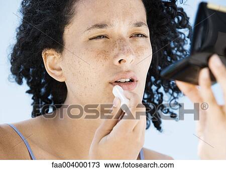 Woman applying lip balm, holding compact View Large Photo Image Stock Image - Woman applying lip balm, holding compact. Fotosearch