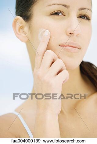 Stock Photo - Woman applying moisturizer to cheek. Fotosearch