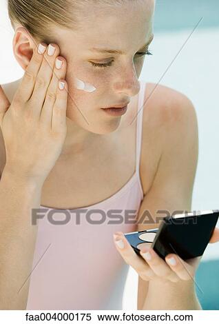 Woman applying sunscreen, looking into compact mirror View Large Photo Image Stock Photography - Woman applying sunscreen, looking into compact mirror. Fotosearch