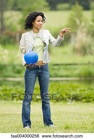 Woman holding ball and pointing out of frame View Large Photo Image Stock Photograph - Woman holding ball and pointing out of frame. Fotosearch