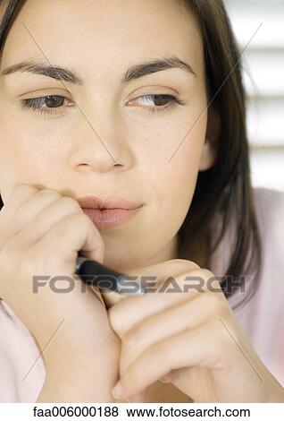 Woman holding pen near face, close-up View Large Photo Image Stock Photo - Woman holding pen near face, close-up. Fotosearch