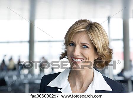 Woman in suit smiling in airport setting, portrait View Large Photo Image Stock Photo - Woman in suit smiling in airport setting, portrait. Fotosearch