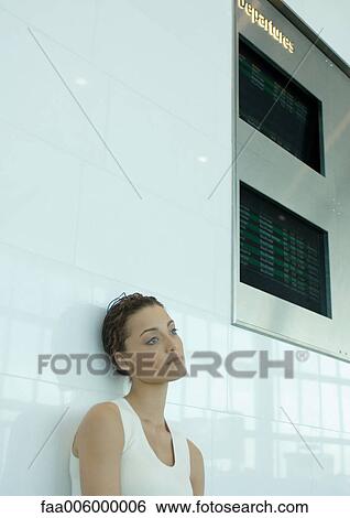 Woman leaning against wall below arrival and departure boards View Large Photo Image Stock Photograph - Woman leaning against wall below arrival and departure boards. Fotosearch