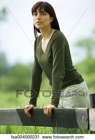 Woman leaning against wooden fence View Large Photo Image Stock Image - Woman leaning against wooden fence. Fotosearch